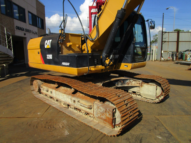 Yellow Caterpillar excavator on a concrete surface with a building and sky in the background.