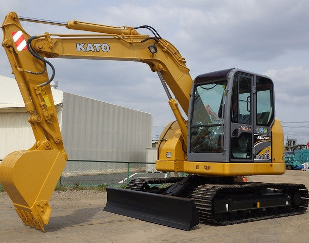 Yellow Kato excavator on a concrete surface with a building in the background. HD308US-6A-6147 Kato