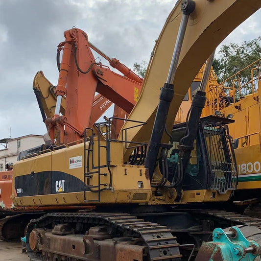 Large yellow excavator on a concrete surface with a cloudy sky in the background