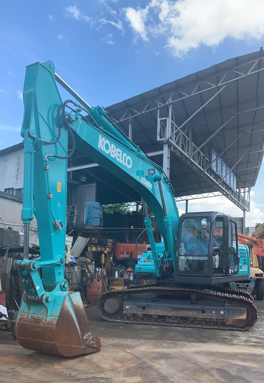 Kobelco excavator on a construction site with a building in the background