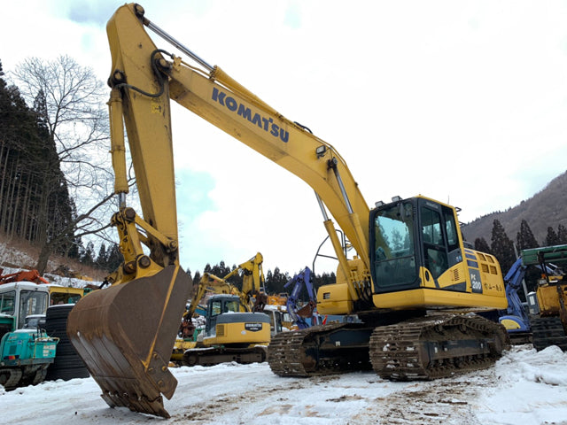 Yellow Komatsu excavator in a snowy construction site with other equipment.
