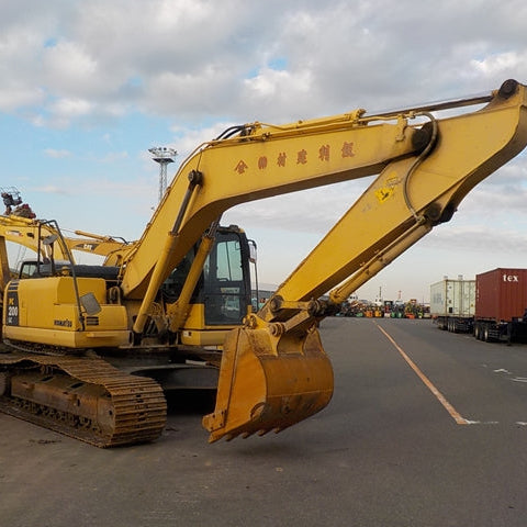 Yellow excavator on a road with a cloudy sky