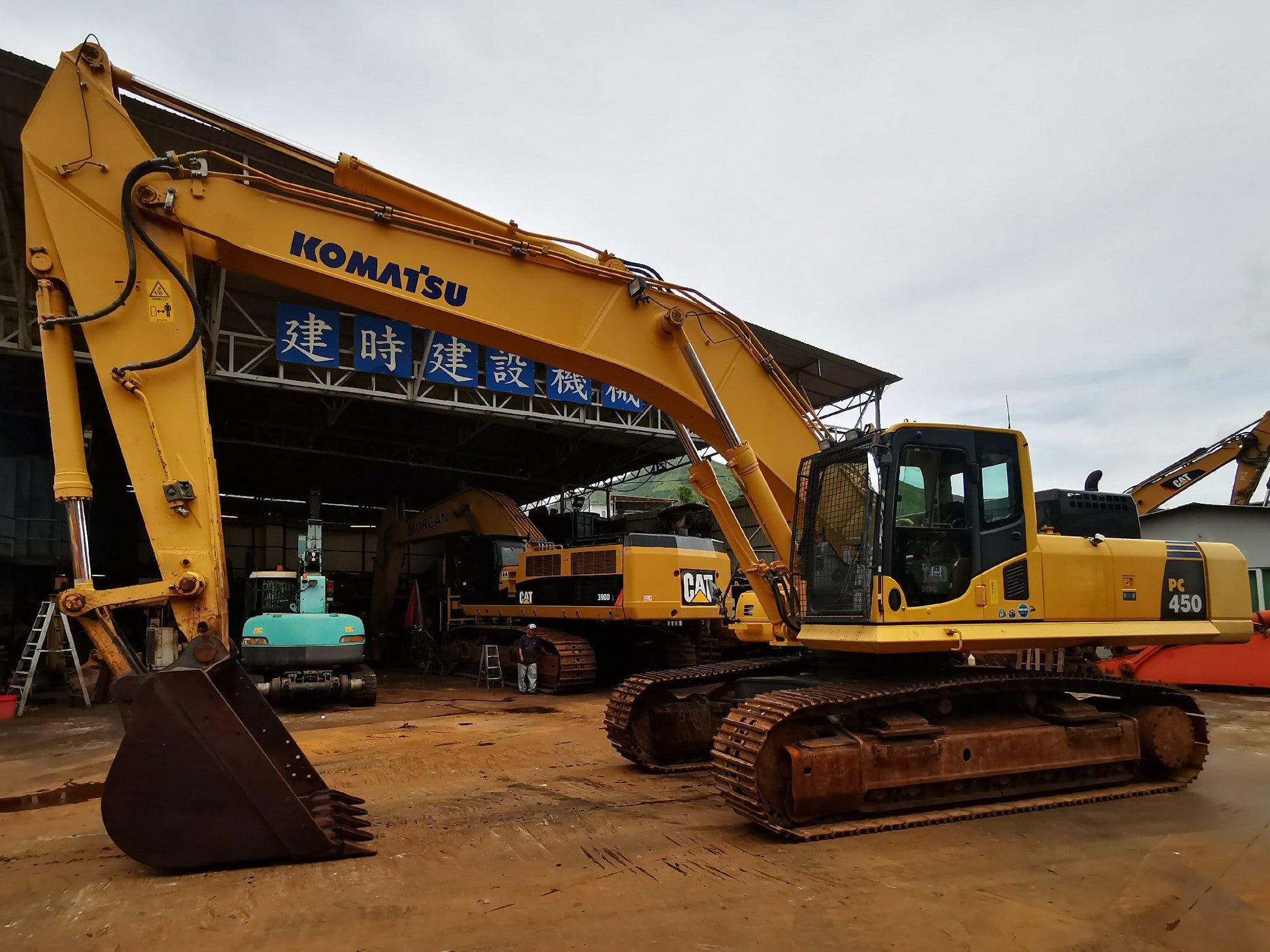 Yellow Komatsu excavator in an outdoor setting with a building in the background