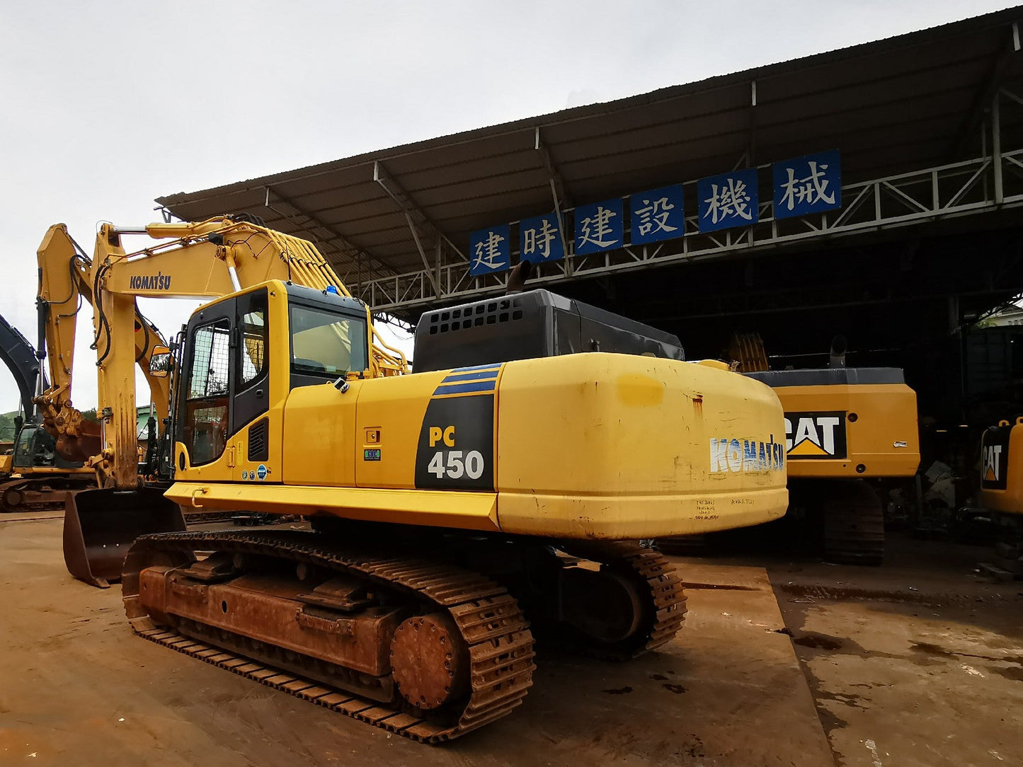 Yellow excavator with a building in the background.