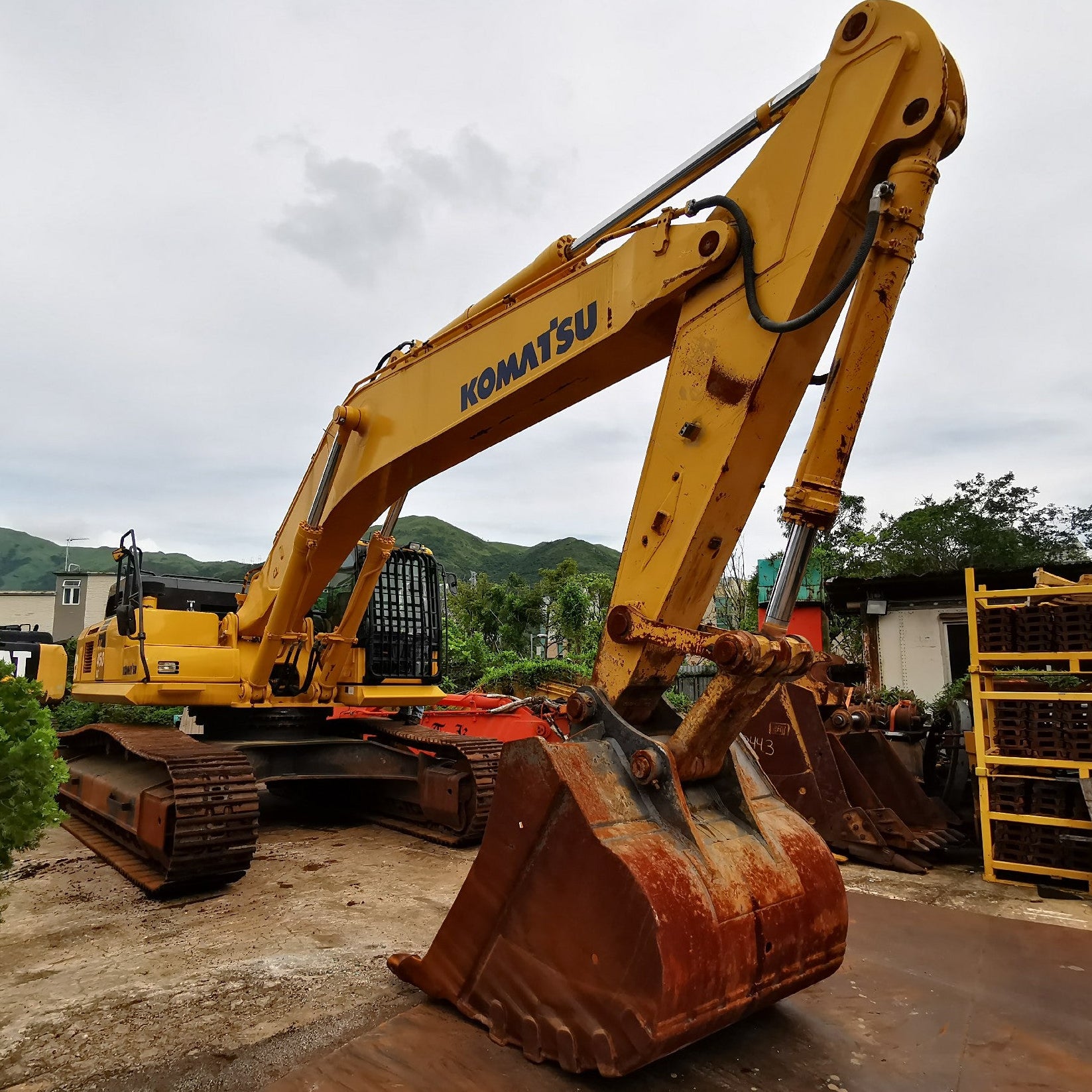 Yellow Komatsu excavator on a construction site with mountains in the background