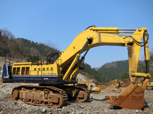 Yellow excavator on a construction site with mountains in the background