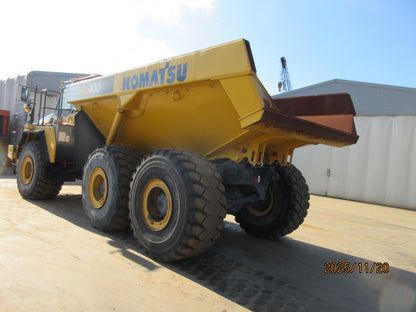 Yellow Komatsu dump truck on a concrete surface with a building in the background.