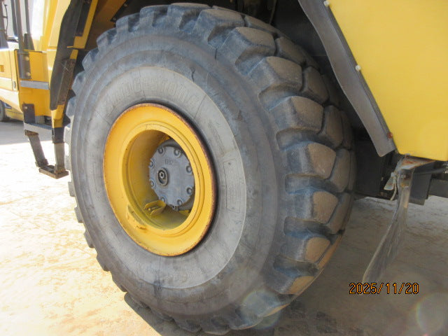 Close-up of a large industrial tire with a yellow rim on a vehicle.