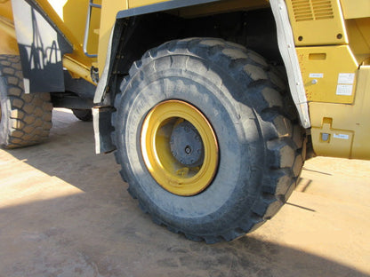 Close-up of a large yellow tire on a piece of heavy machinery with a date stamp in the corner.