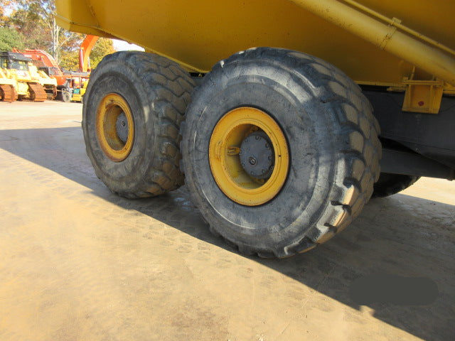 Close-up of large yellow dump truck tires on a construction site.